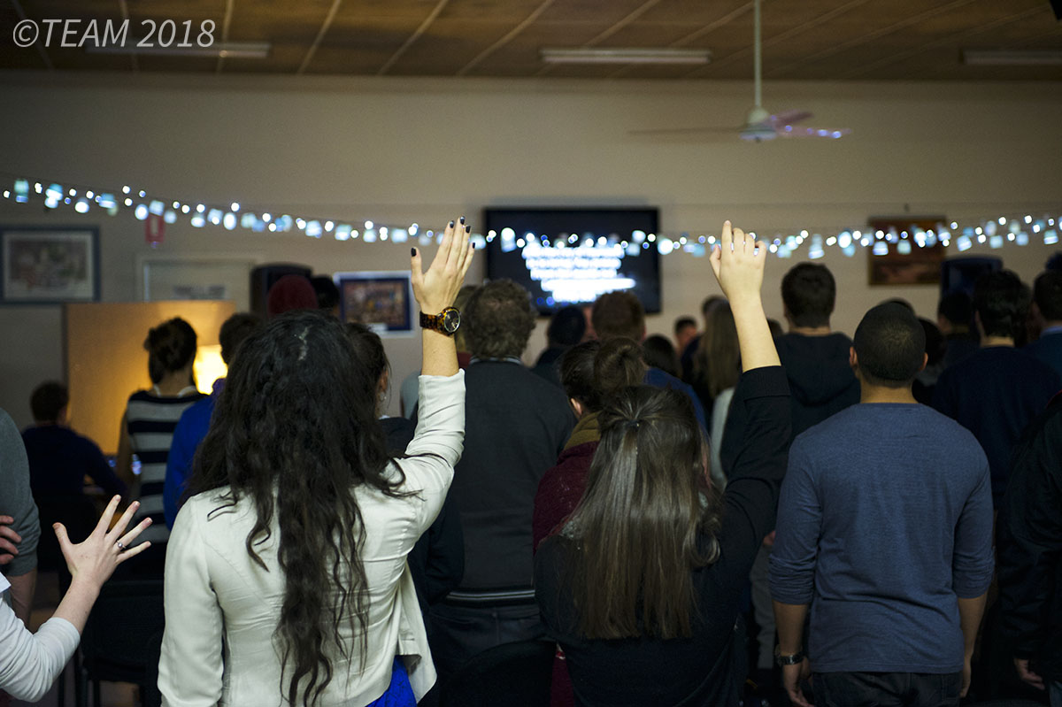 People raise their hands in worship at a church ministry happening in Australia