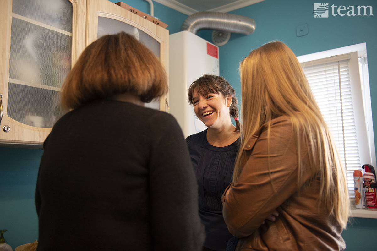 Three women stand and talk