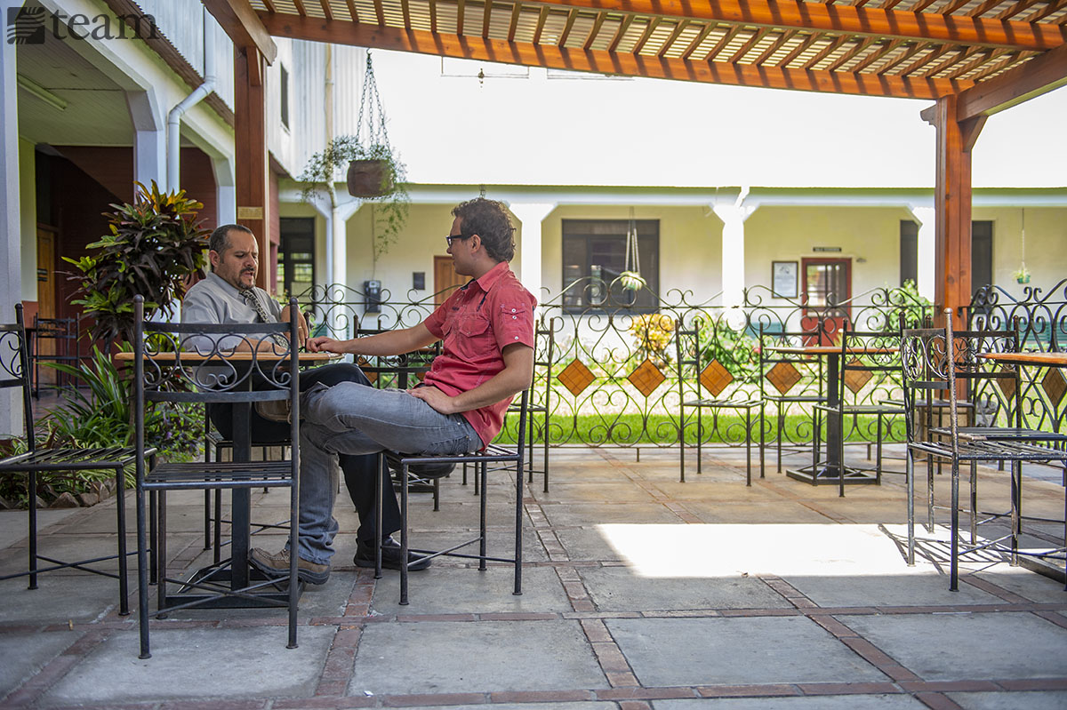 Two men sit outside at a table and talk. Feature photo: Preparing for missions during COVID-19