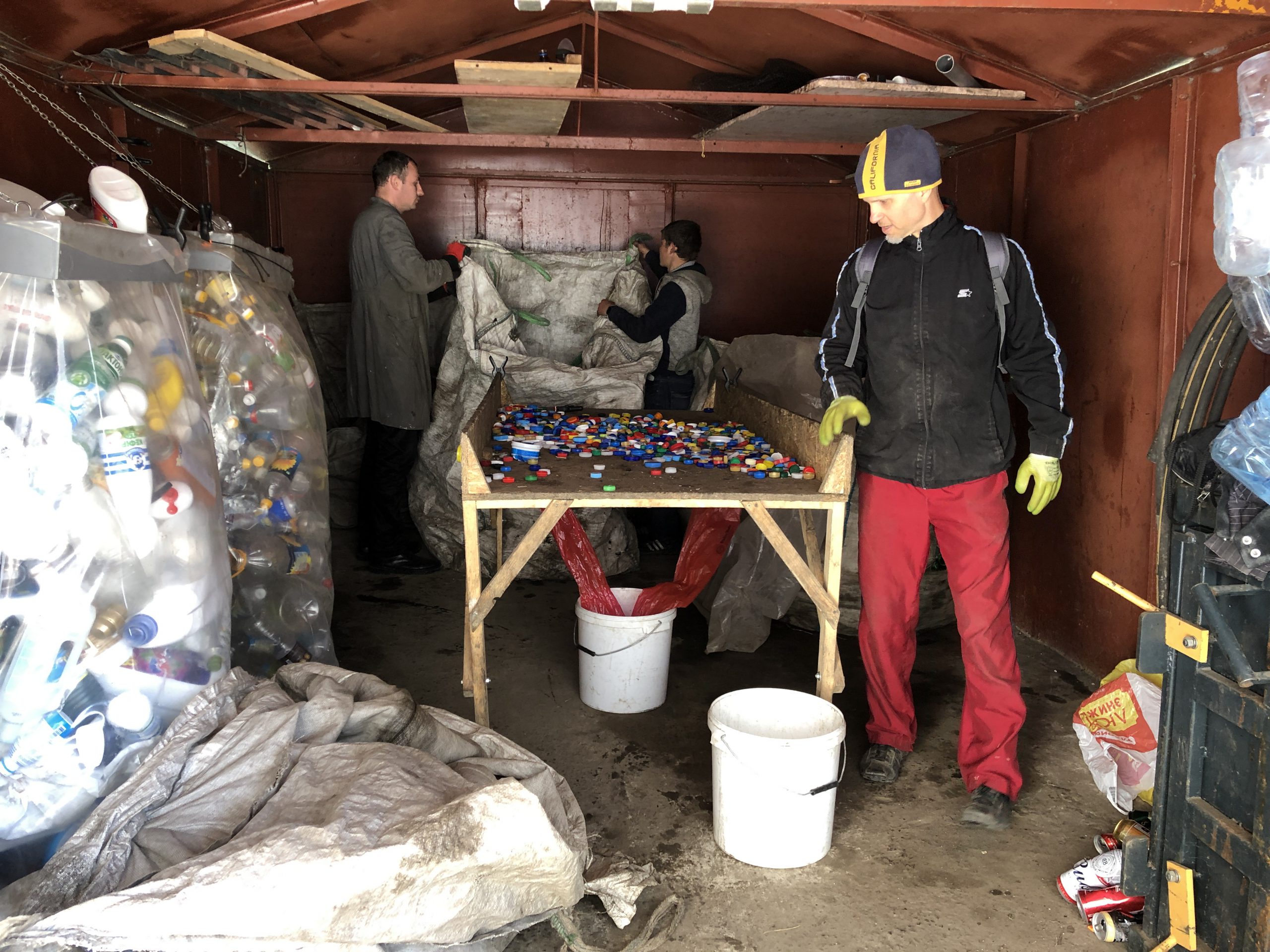 Men sort bottle caps as part of recycling project