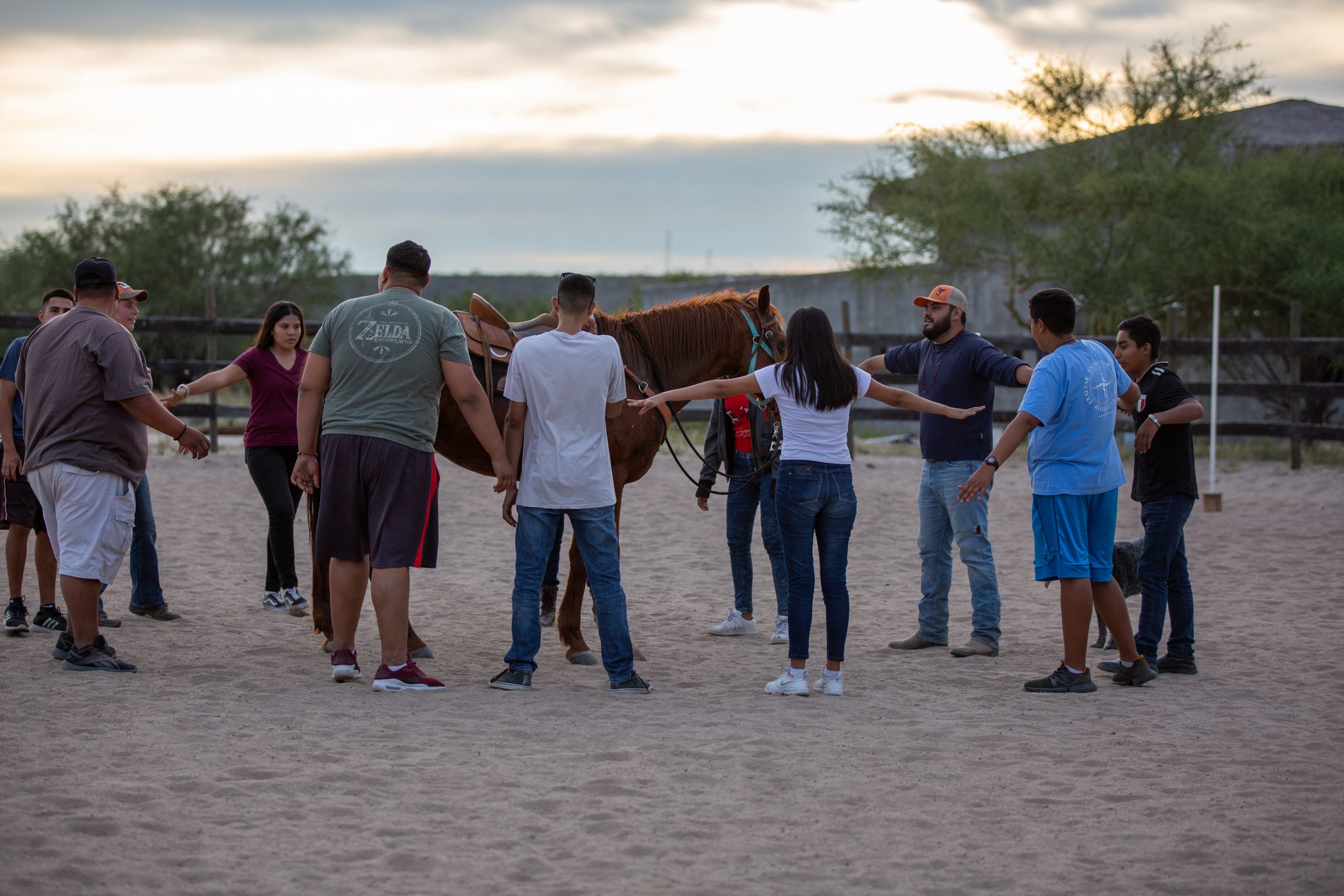 Teens stand in a circle around a horse at Rancho el Camino, where many short-term missionaries serve