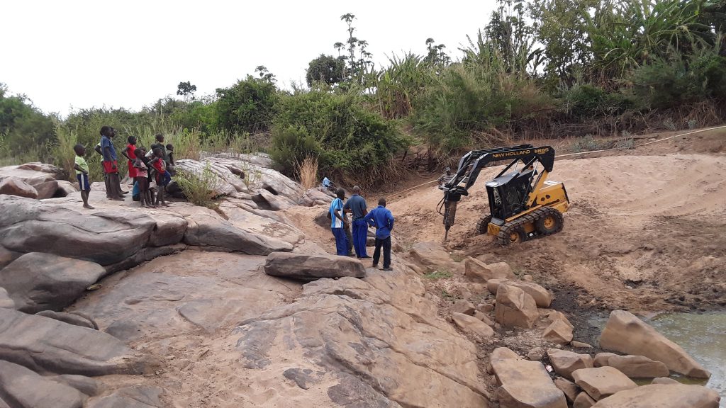 Local staff learn how to use a machine to break up rocks that block water flow for the hospital. 