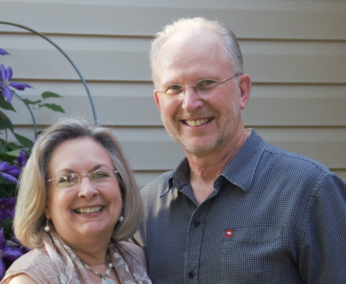 Senior couple in front of some flowers.