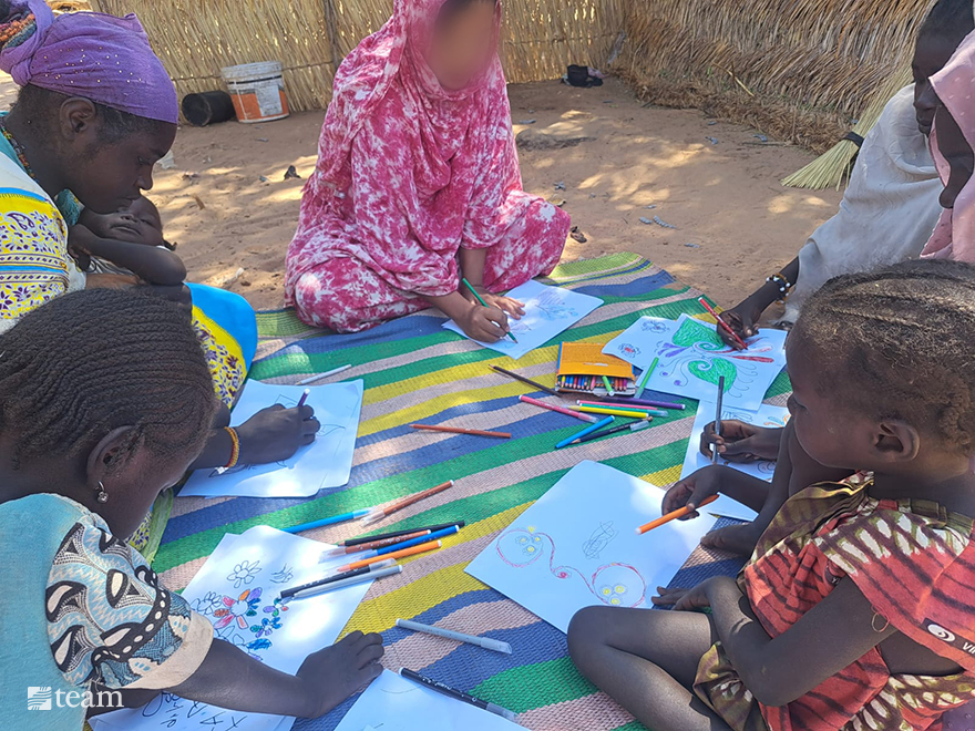 Woman coloring on a mat with children.