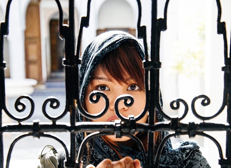 Asian woman standing behind a gate.