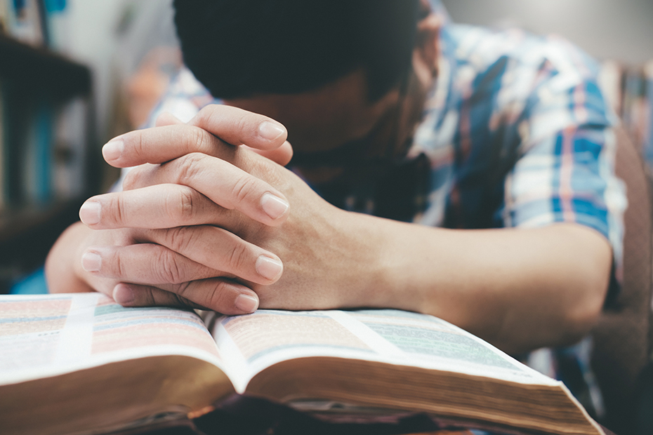 Man praying over a Bible.