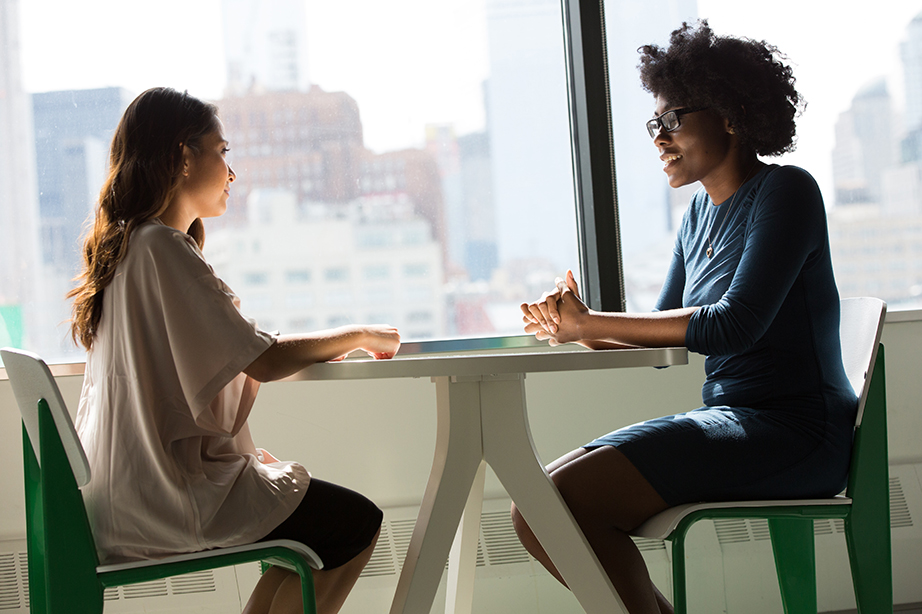 Two ladies sitting at a table talking.