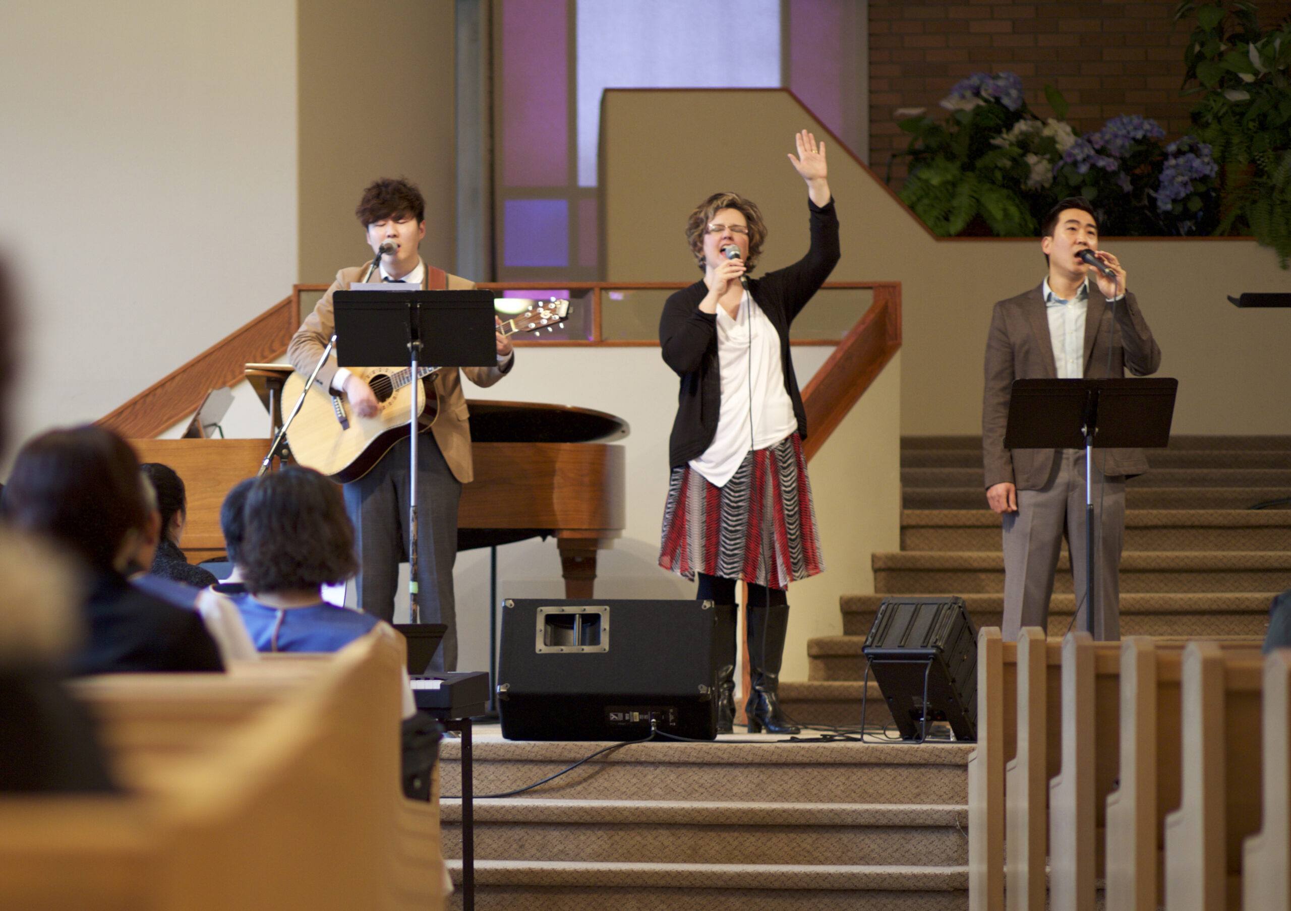 Three people on stage leading worship.