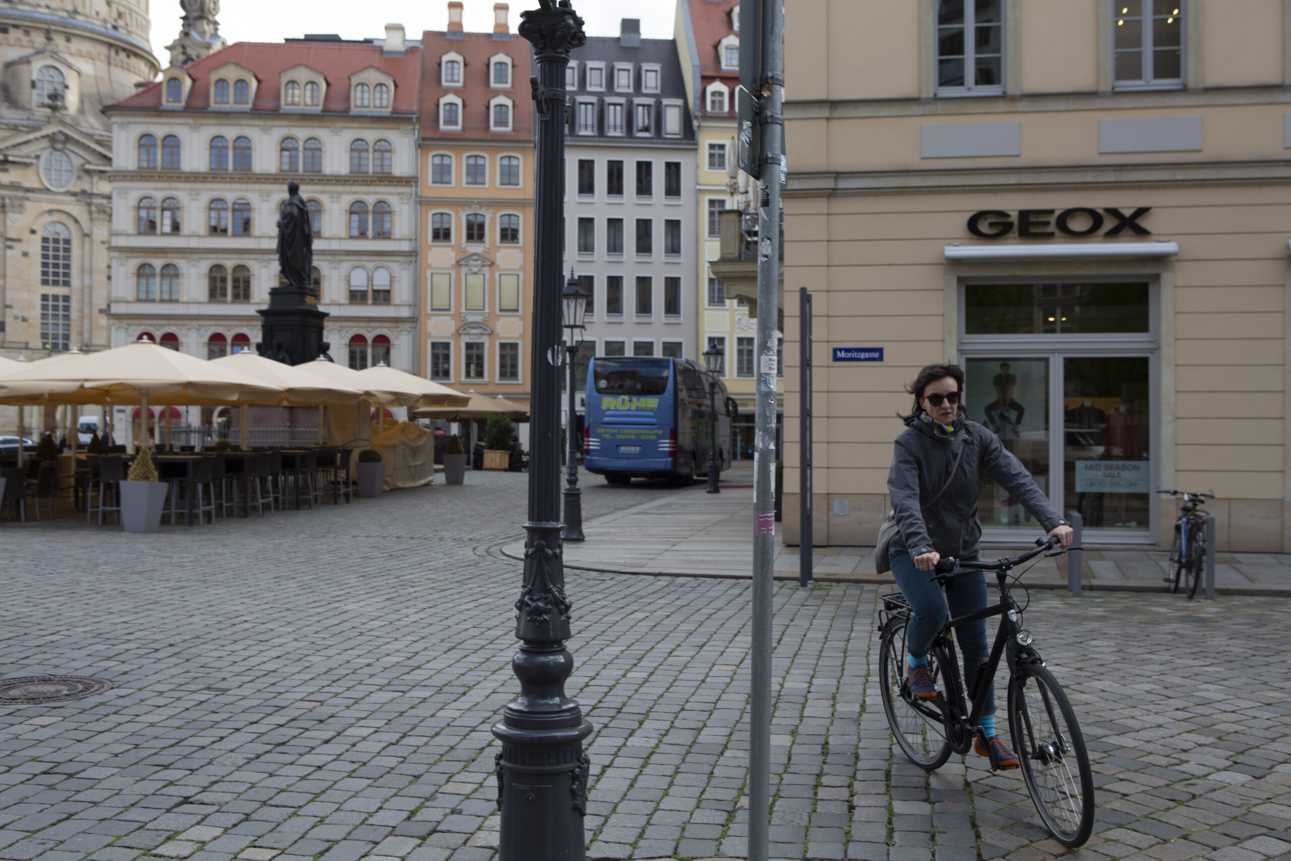 Woman riding her bike on a cobblestone street.