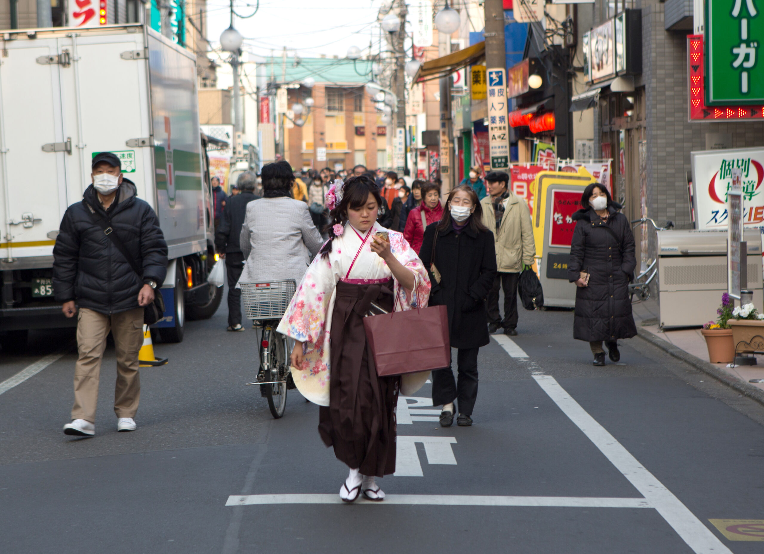 Woman walking down the street looking at her phone.