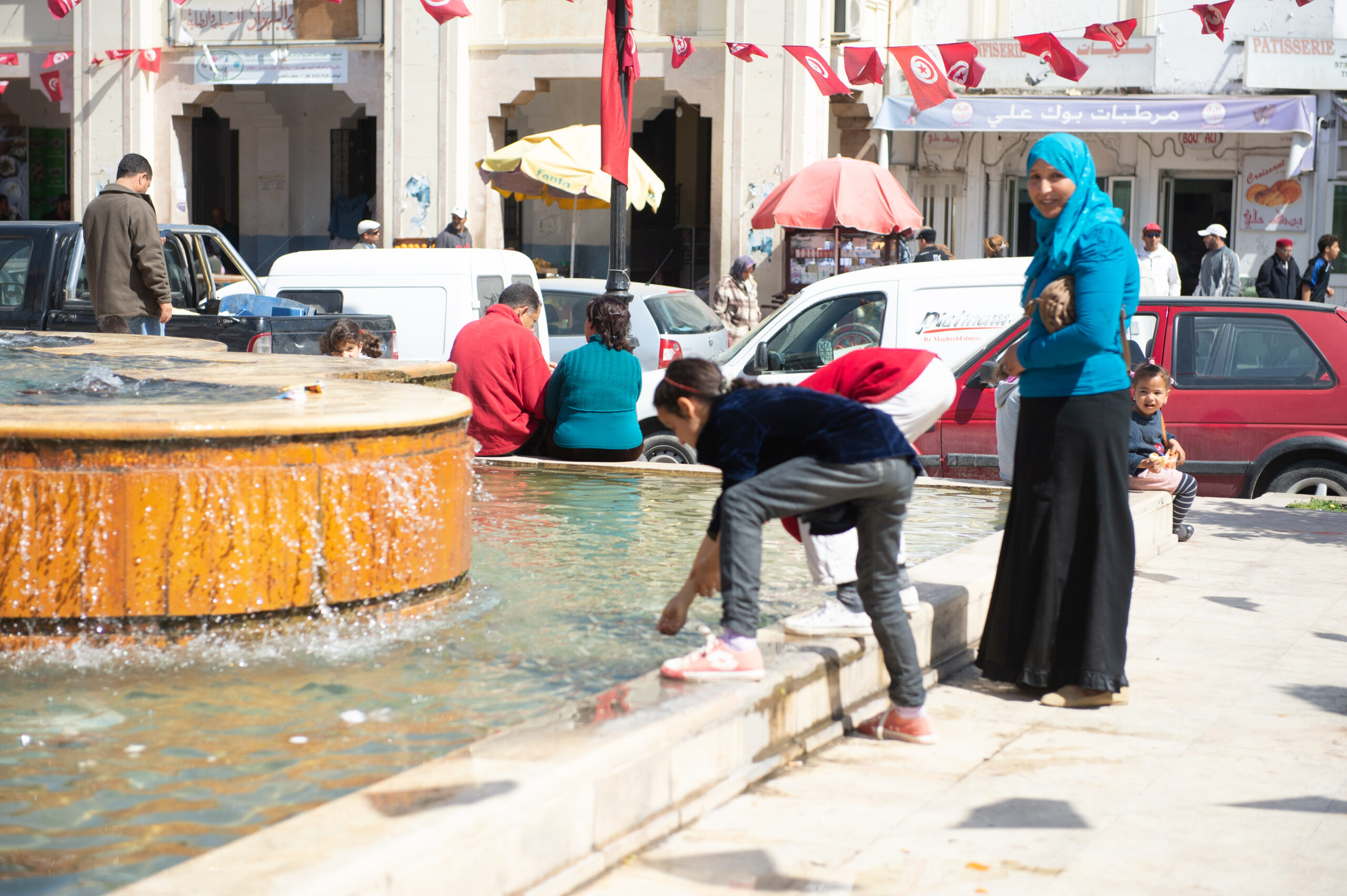 Young girl reaching in a fountain.