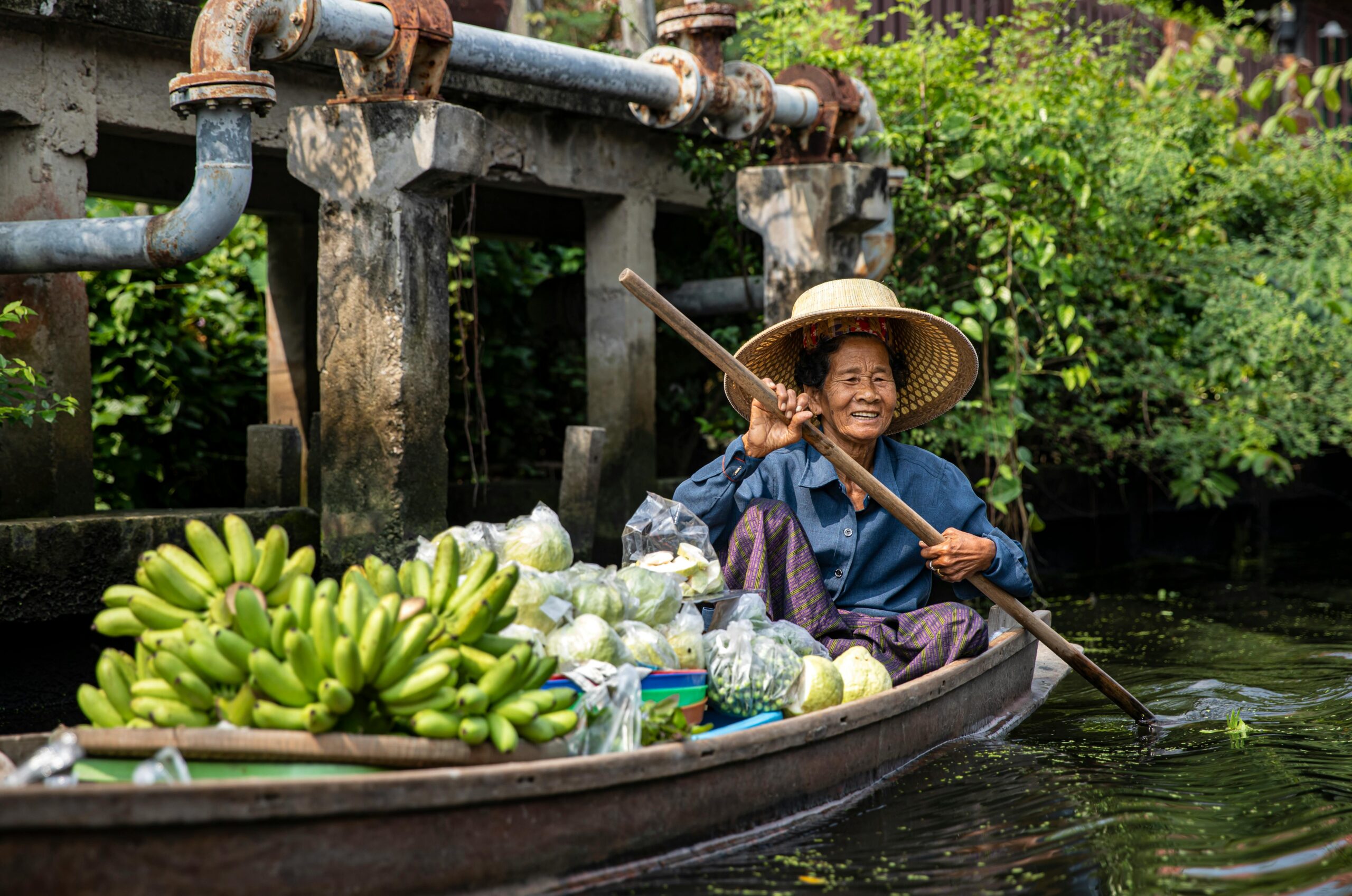 Woman in a boat with various fruits and vegetables.