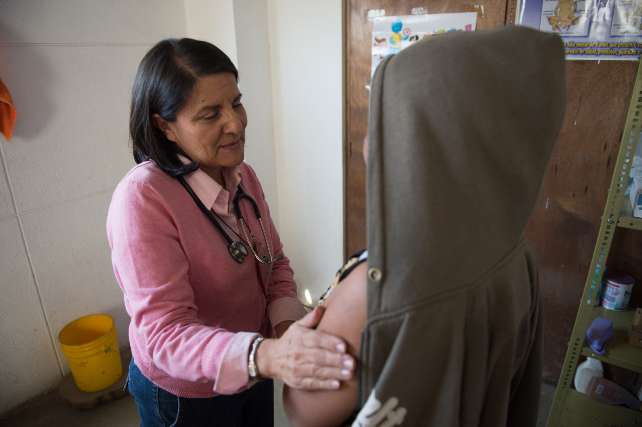 A doctor prays over a patient at her checkup.