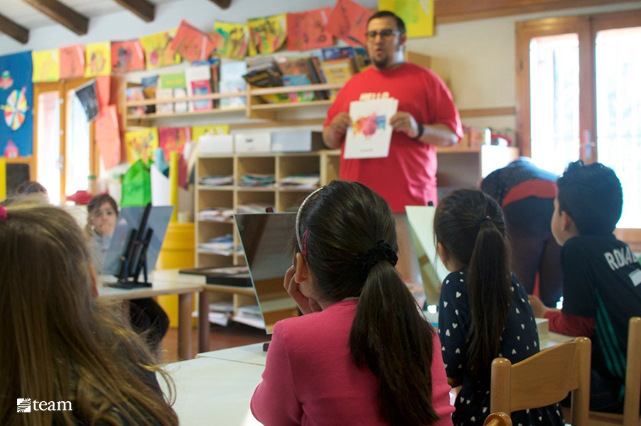 Teacher standing in front of kids teaching art class.