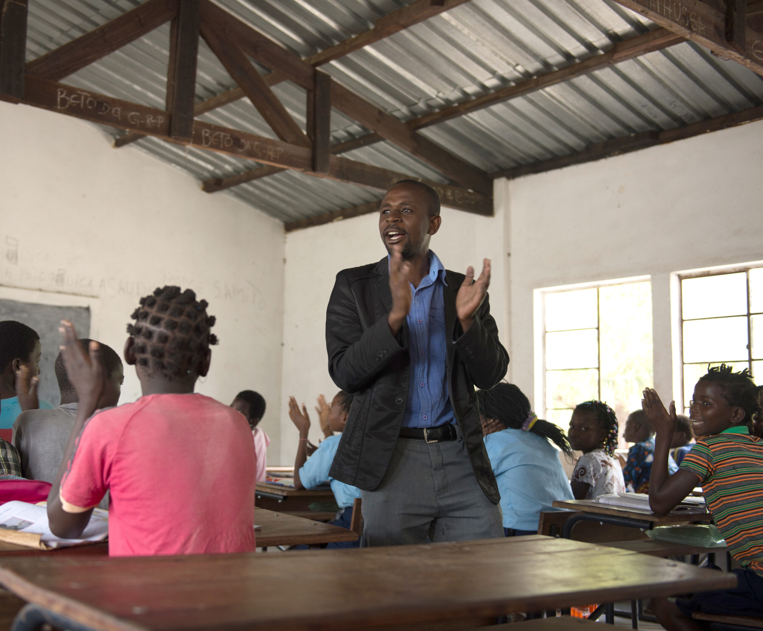 A teacher walking through the classroom clapping and singing.