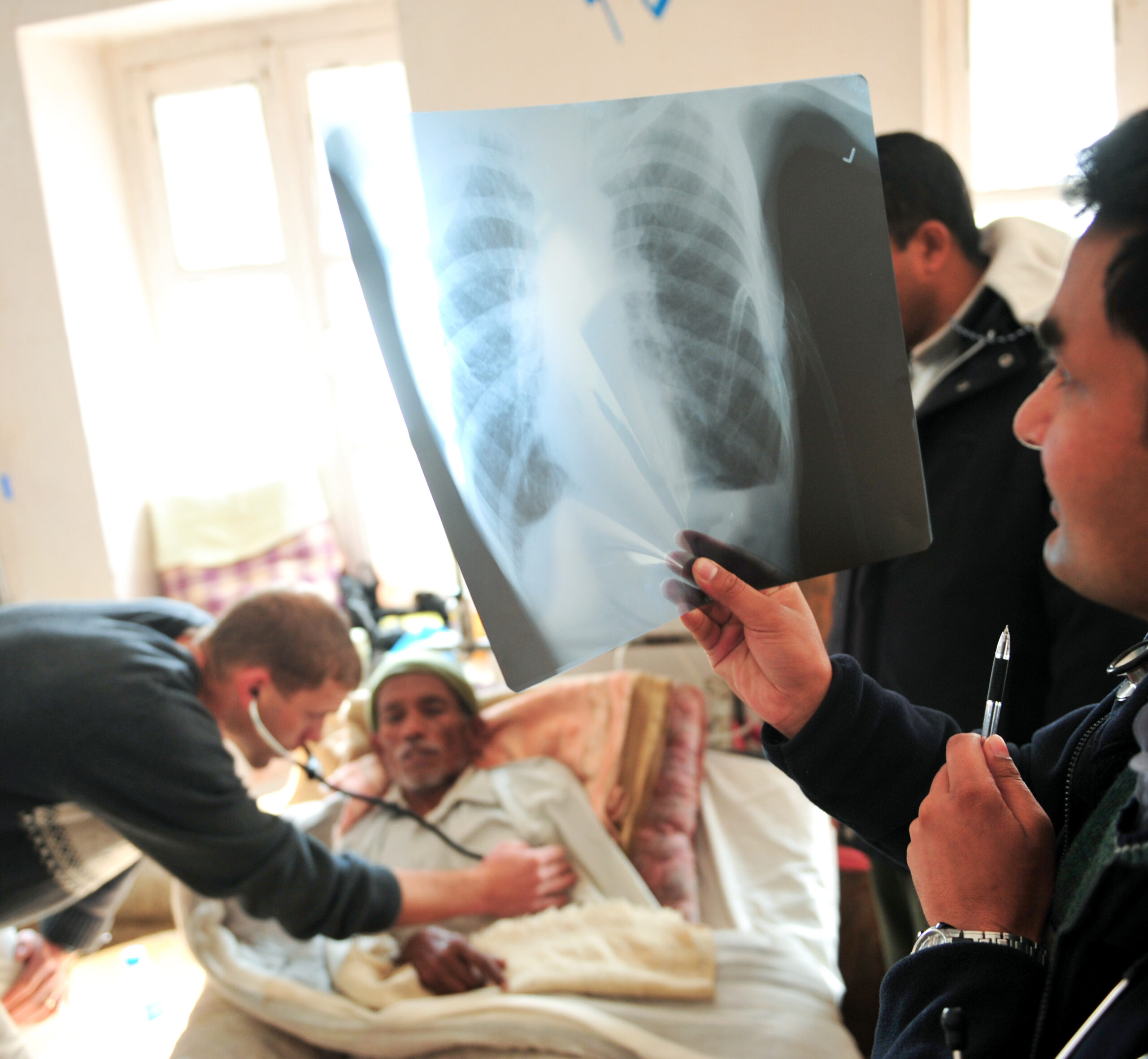 A doctor looking at a chest xray next to the patient in bed.