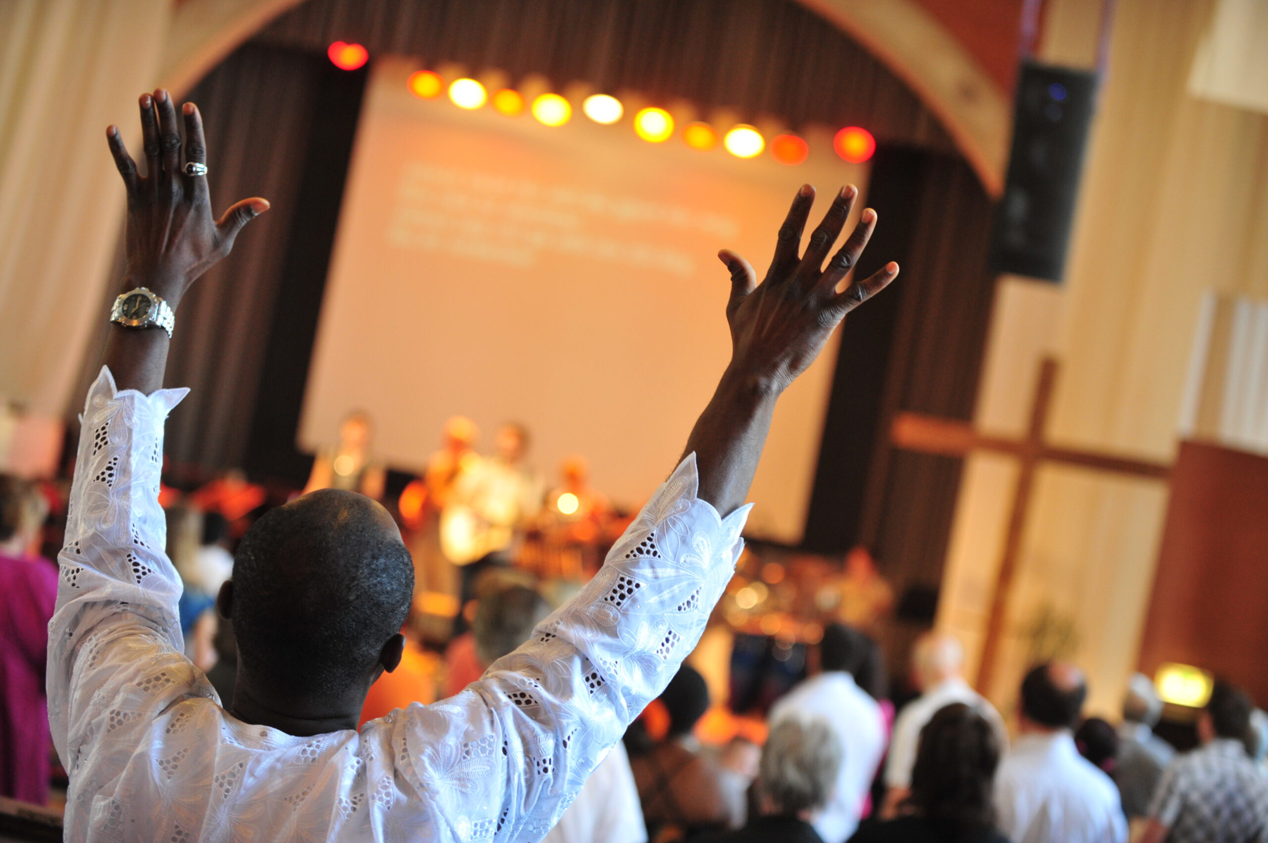 A man raising his hands in worship during a church service.