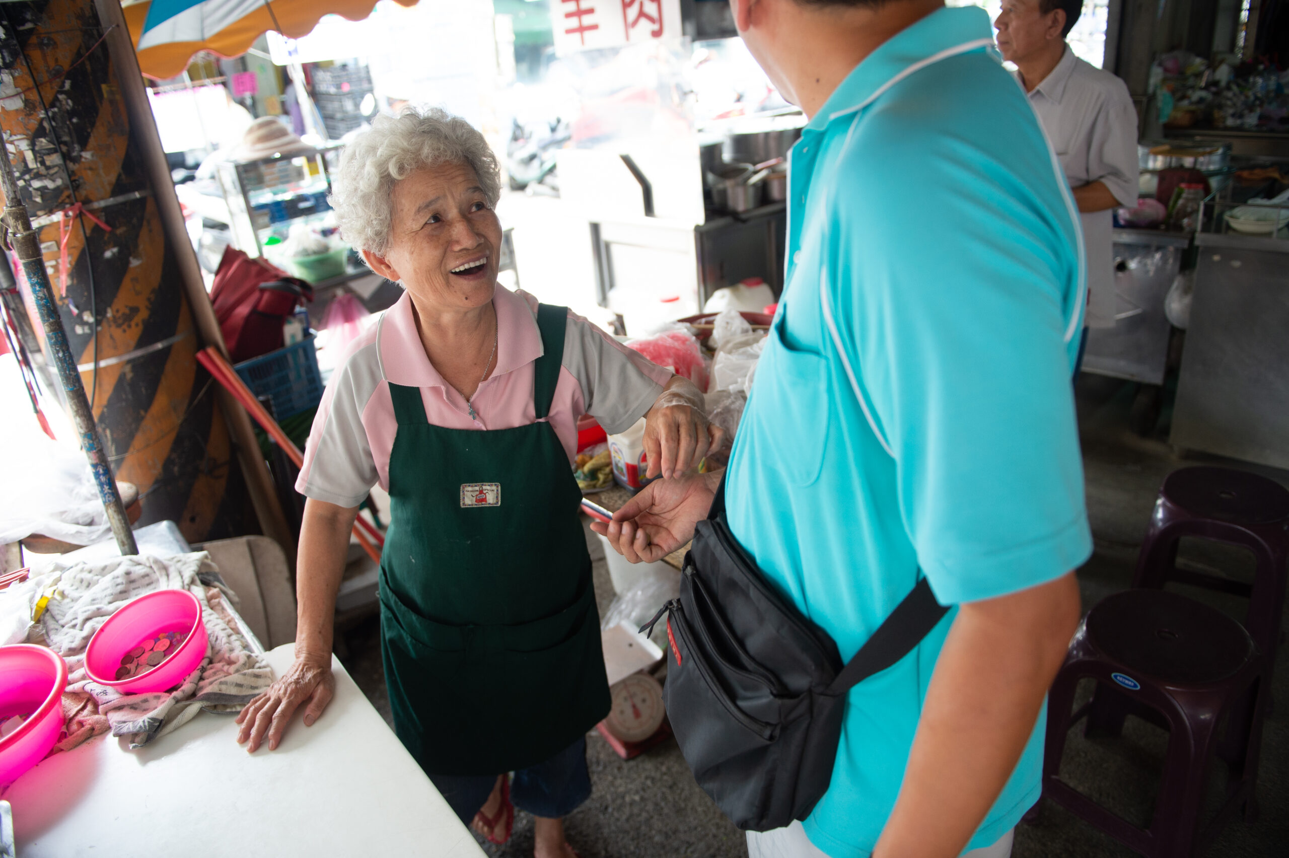 Two Asian people chatting at an open market.