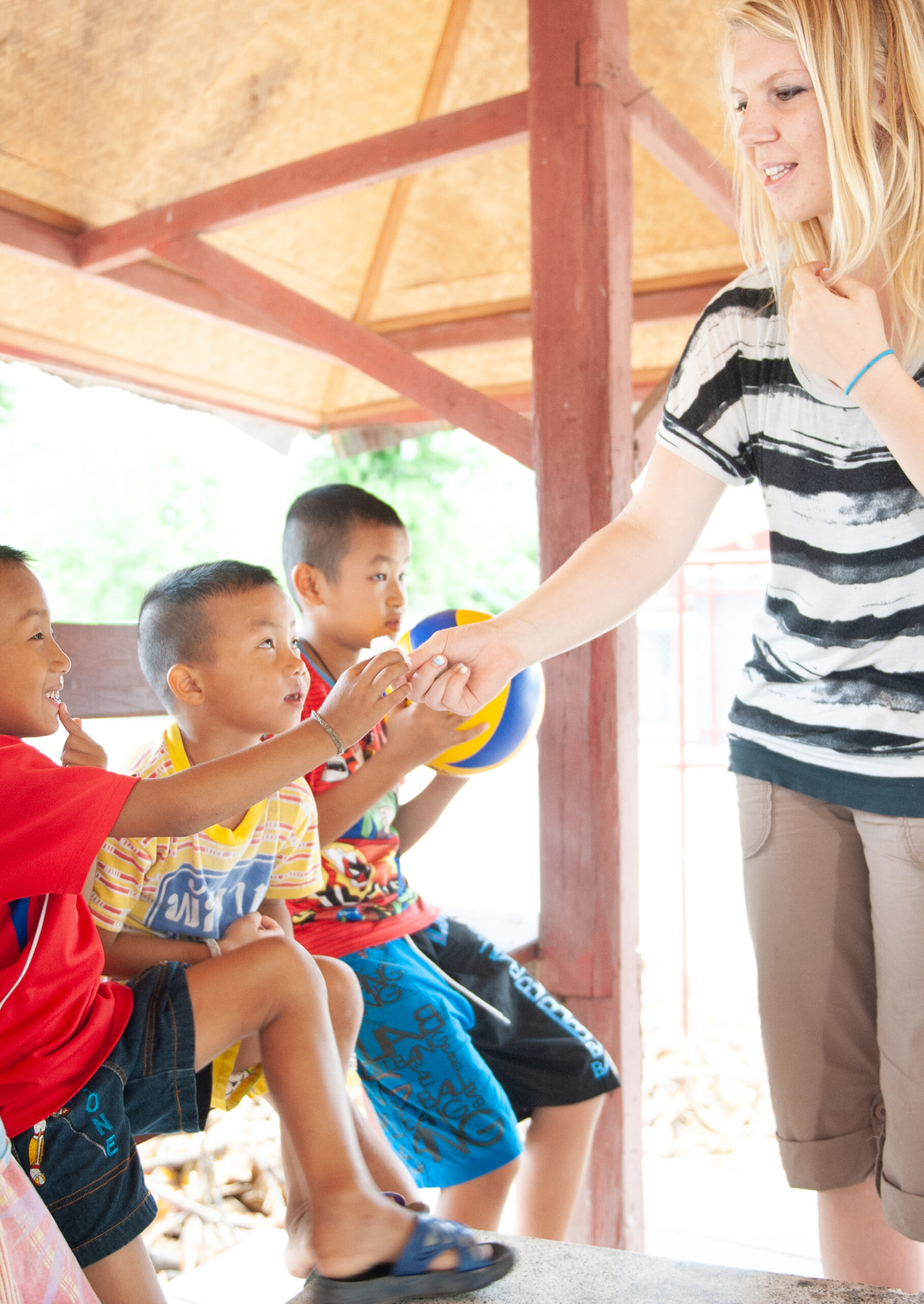 A girl handing a young boy a snack.