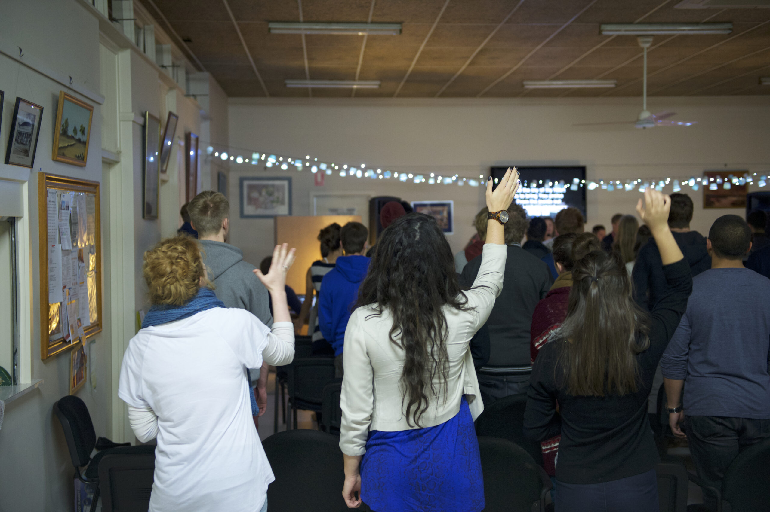 A congregation raises their hands during worship songs at a church service.