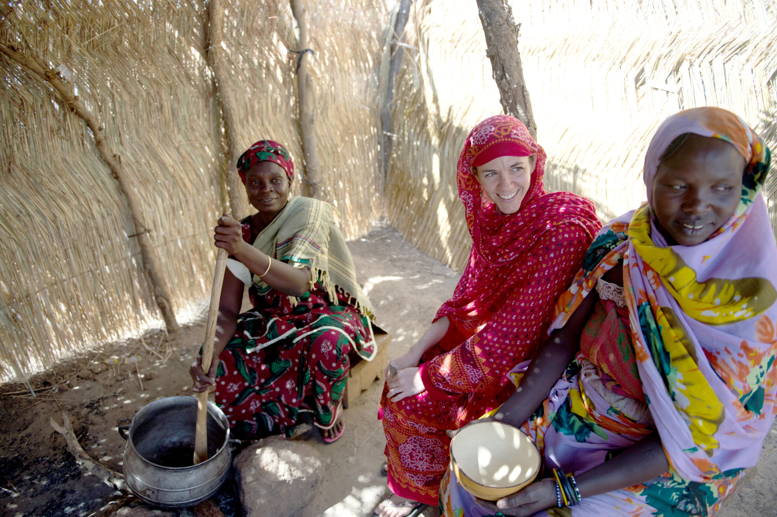 A group of ladies sit together cooking and talking.