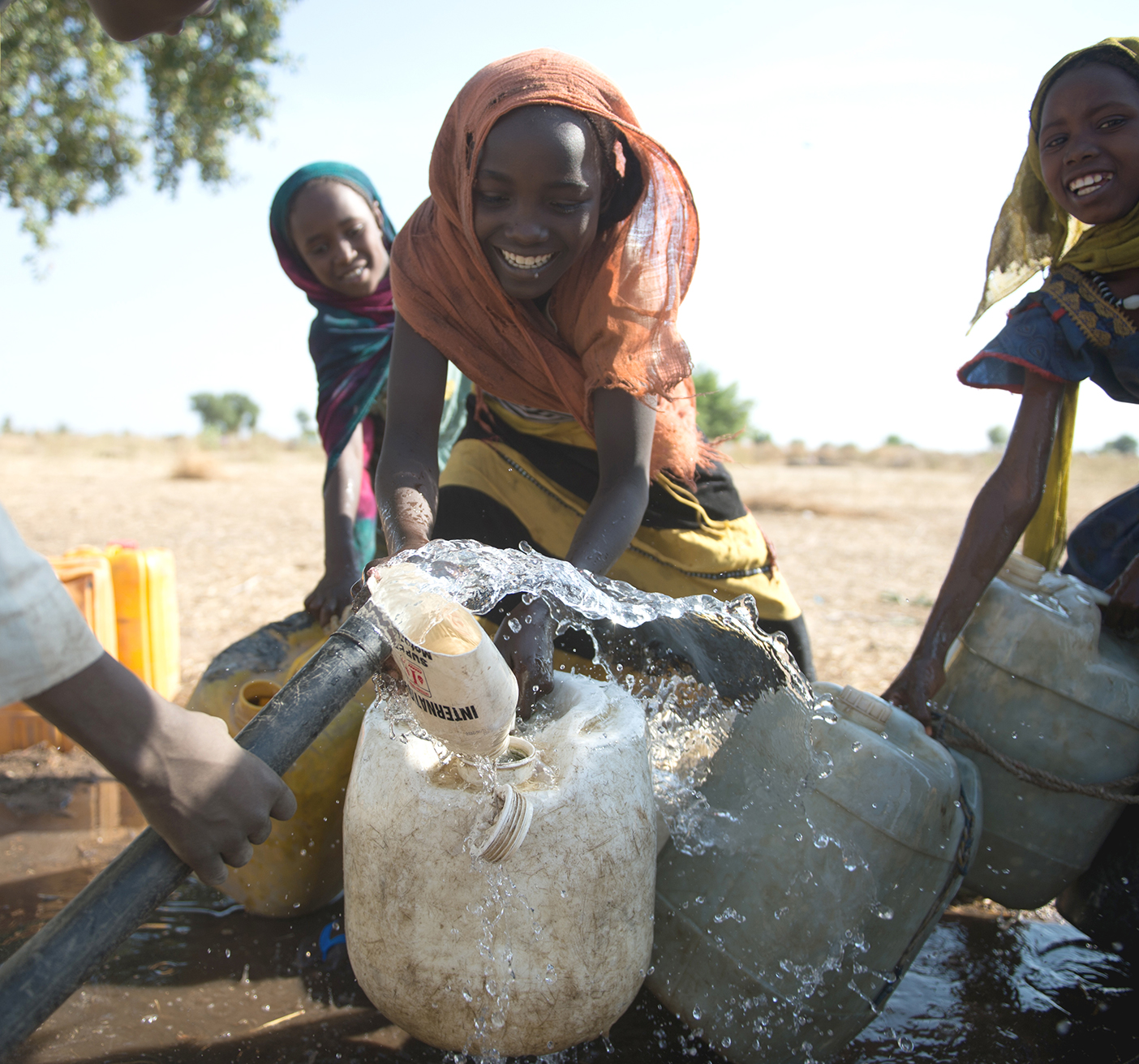 A group of girls fill their containers with water in Africa.