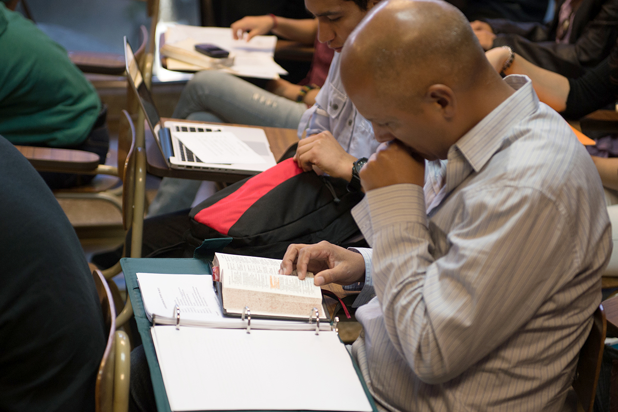 A man is reading his Bible during a seminary class.