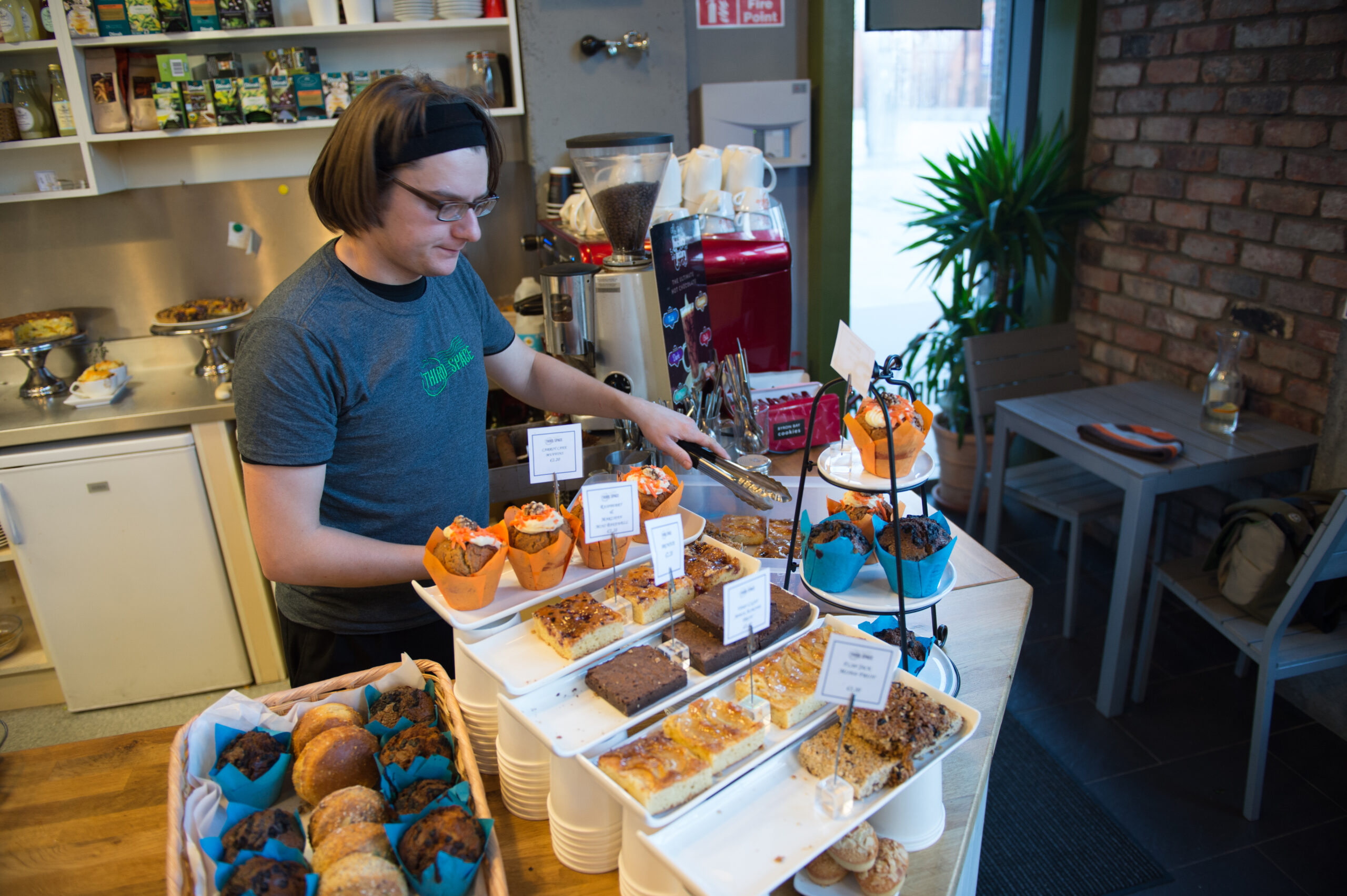 A man serves pastries at a shop.