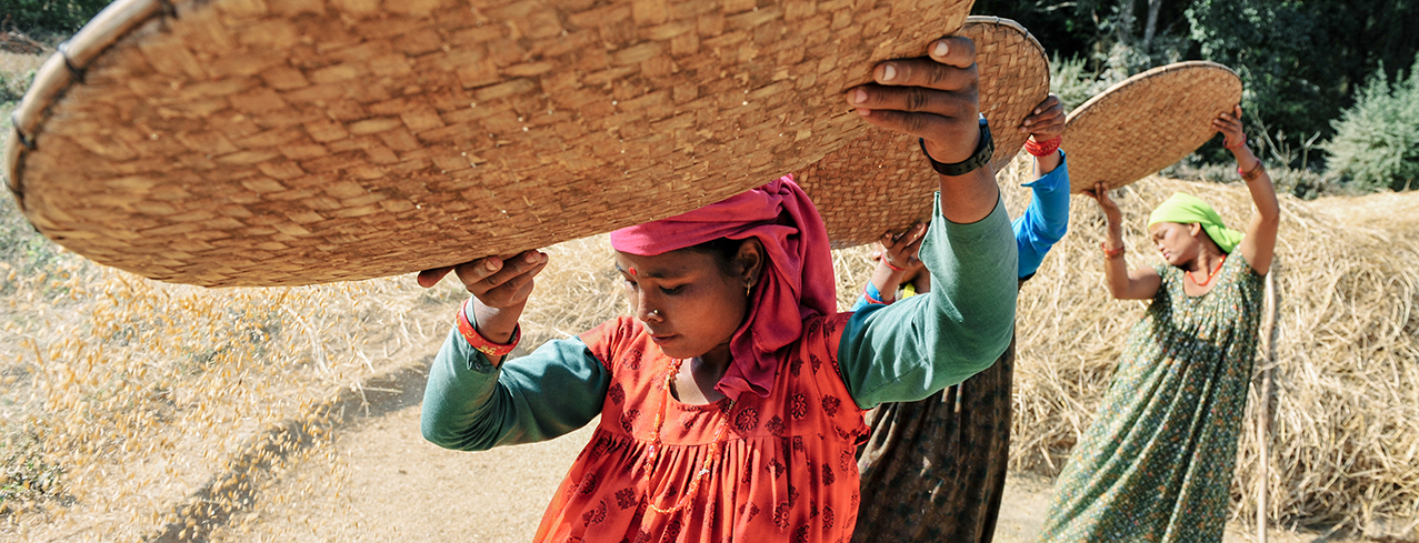 Three girls spreading seeds in a field.