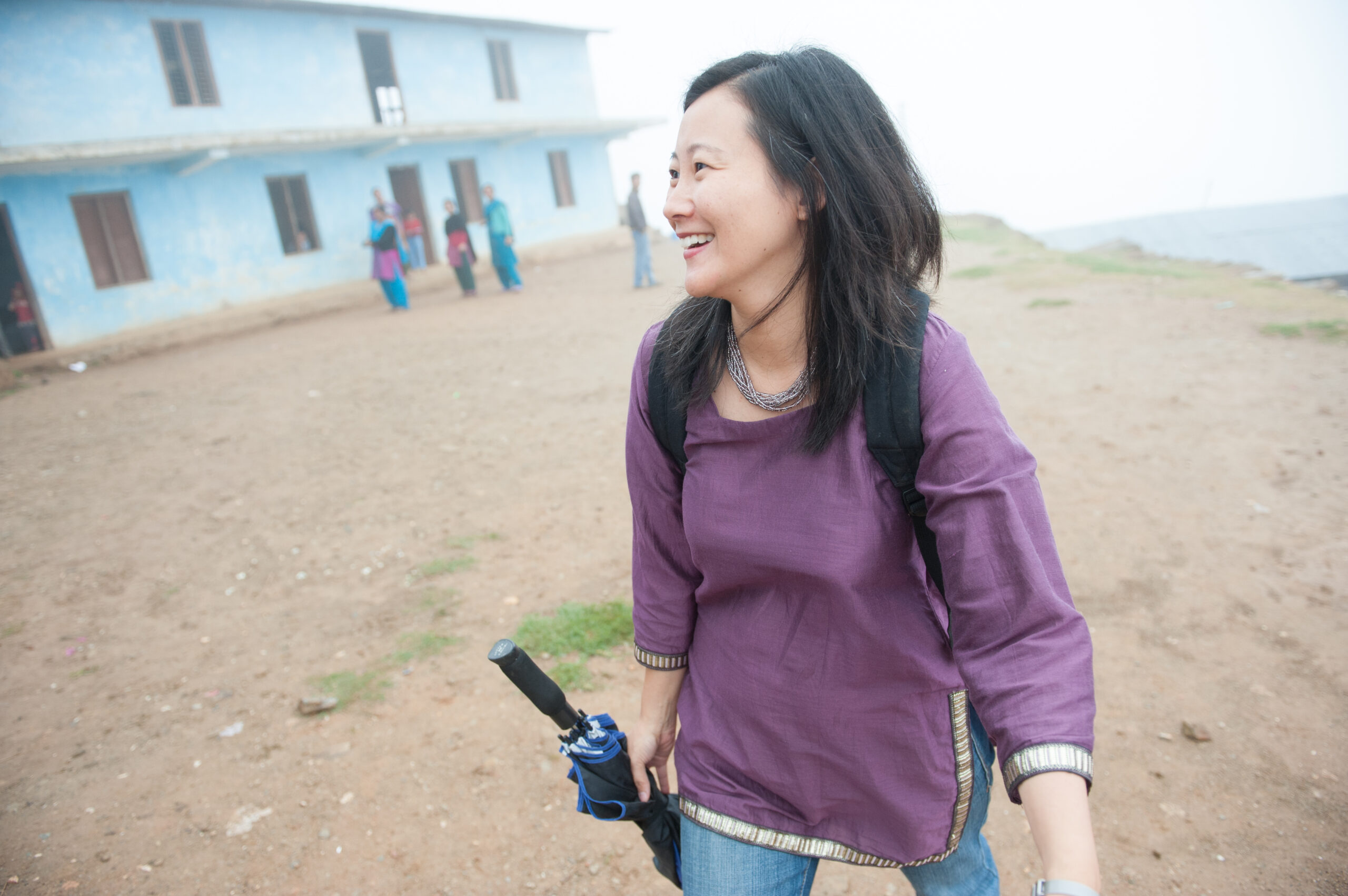 A lady walking with an umbrella and smiling.