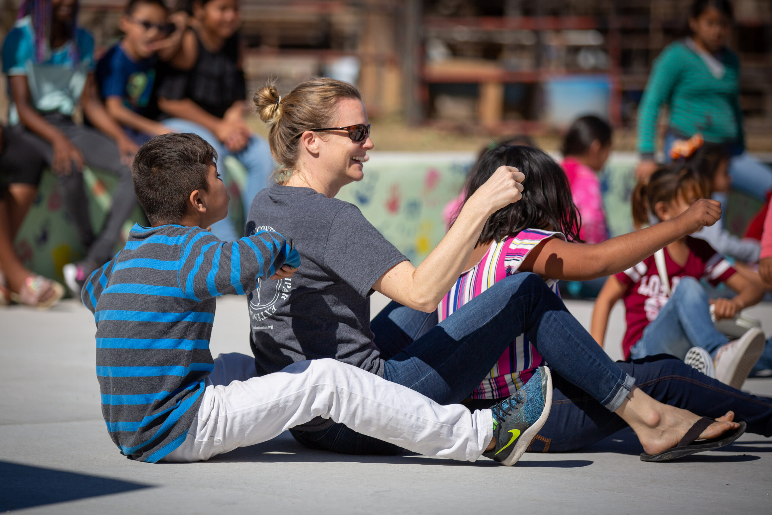 A woman plays games with several children on the ground.