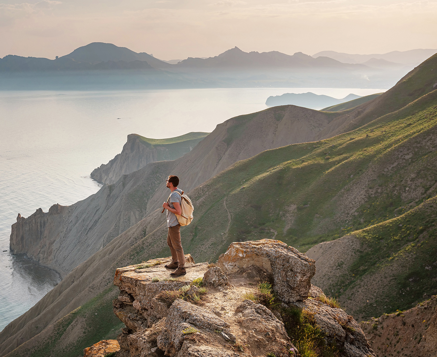 A young man stands looking out over the ocean.