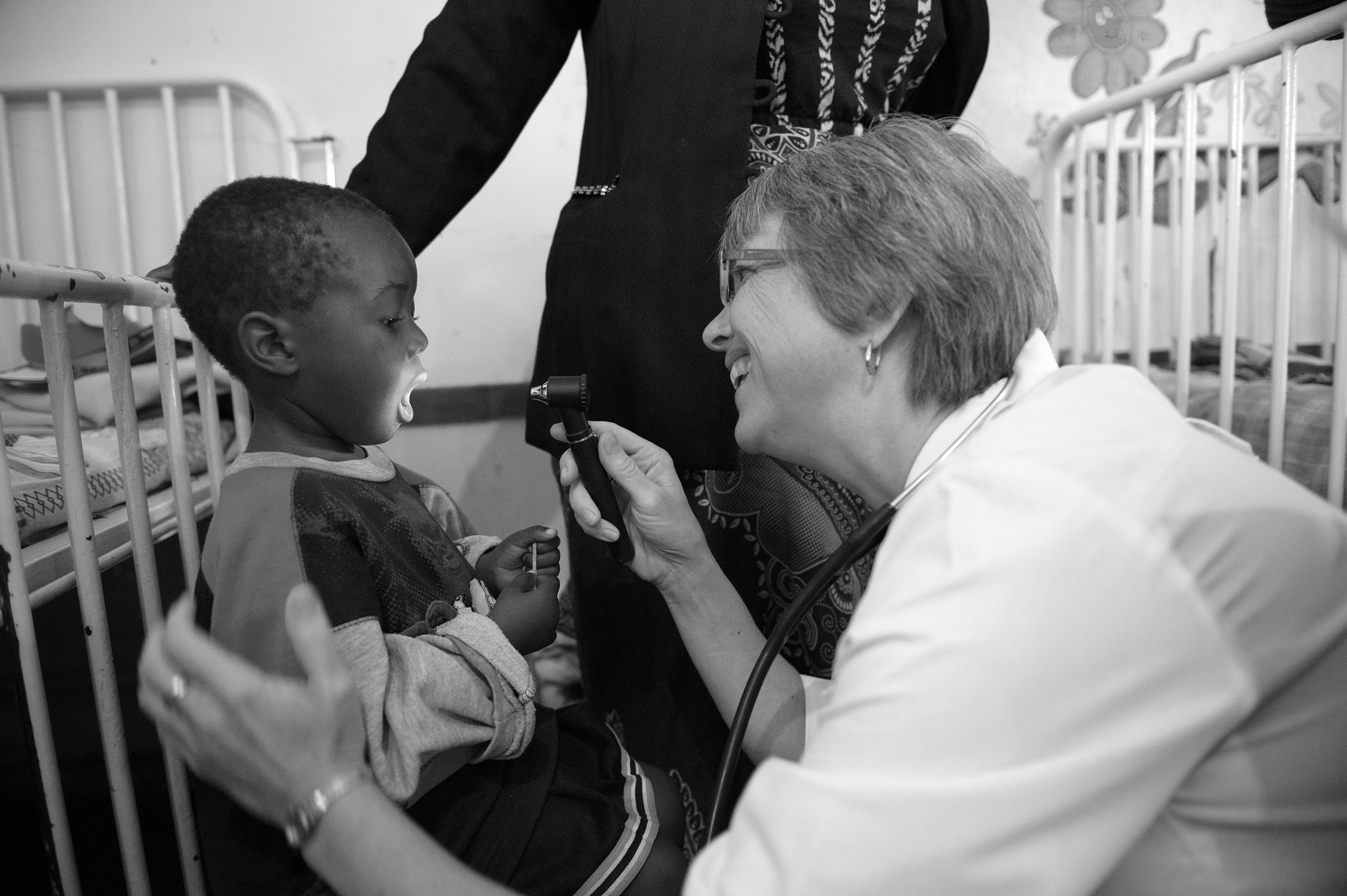 A female doctor looks inside a young boy's mouth.