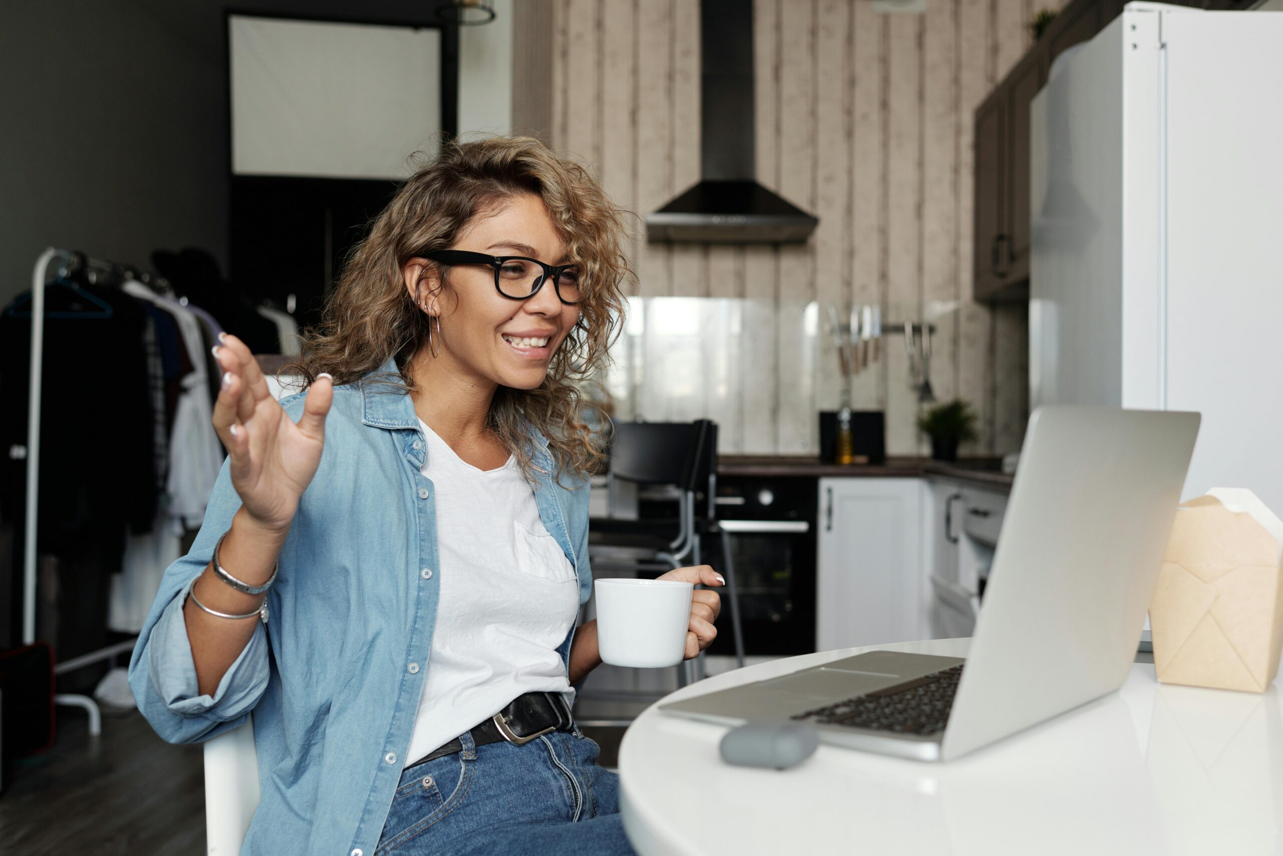 A woman at her computer having an online conversation while holding a mug.