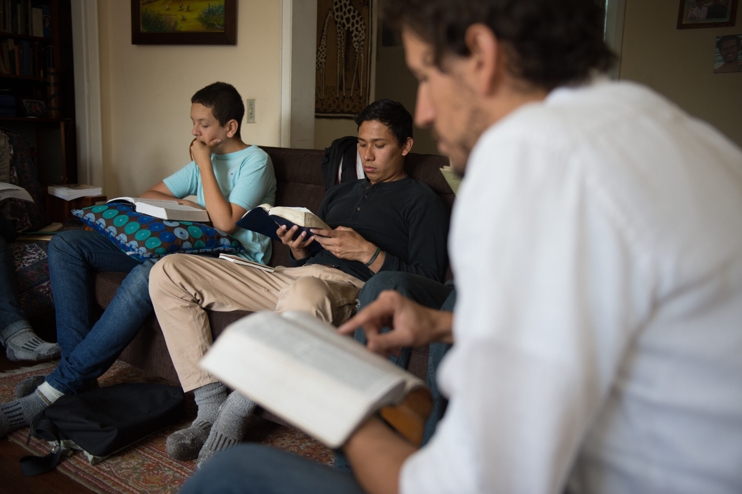 Three young men sitting on couches reading their Bibles.