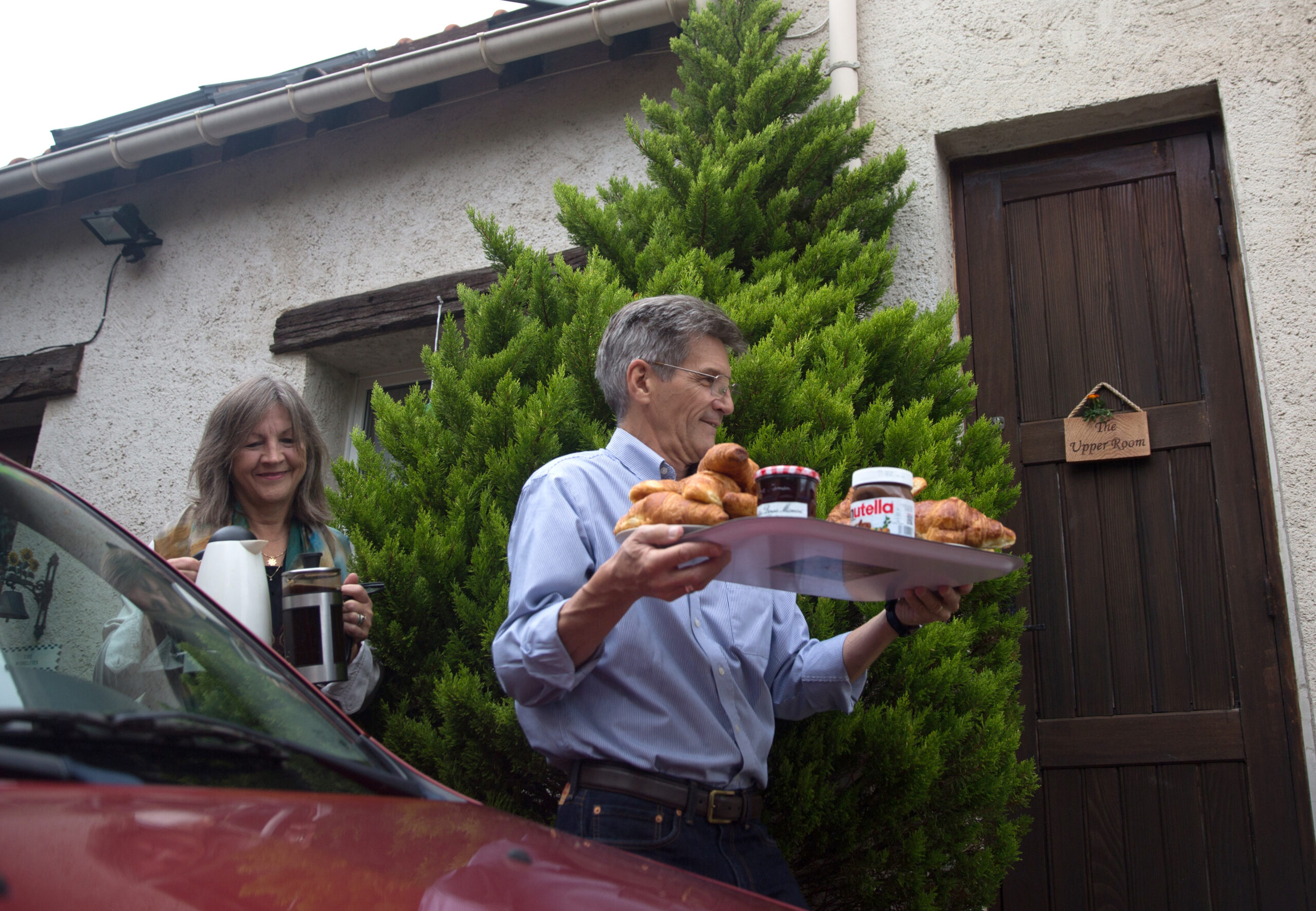 A man and woman carrying pastries, jelly, and coffee.