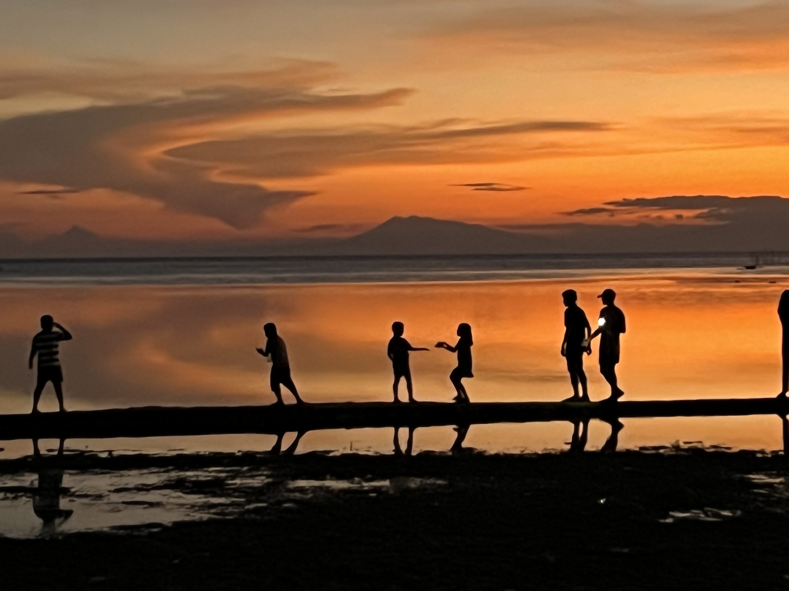 Children playing at the ocean at sunset.