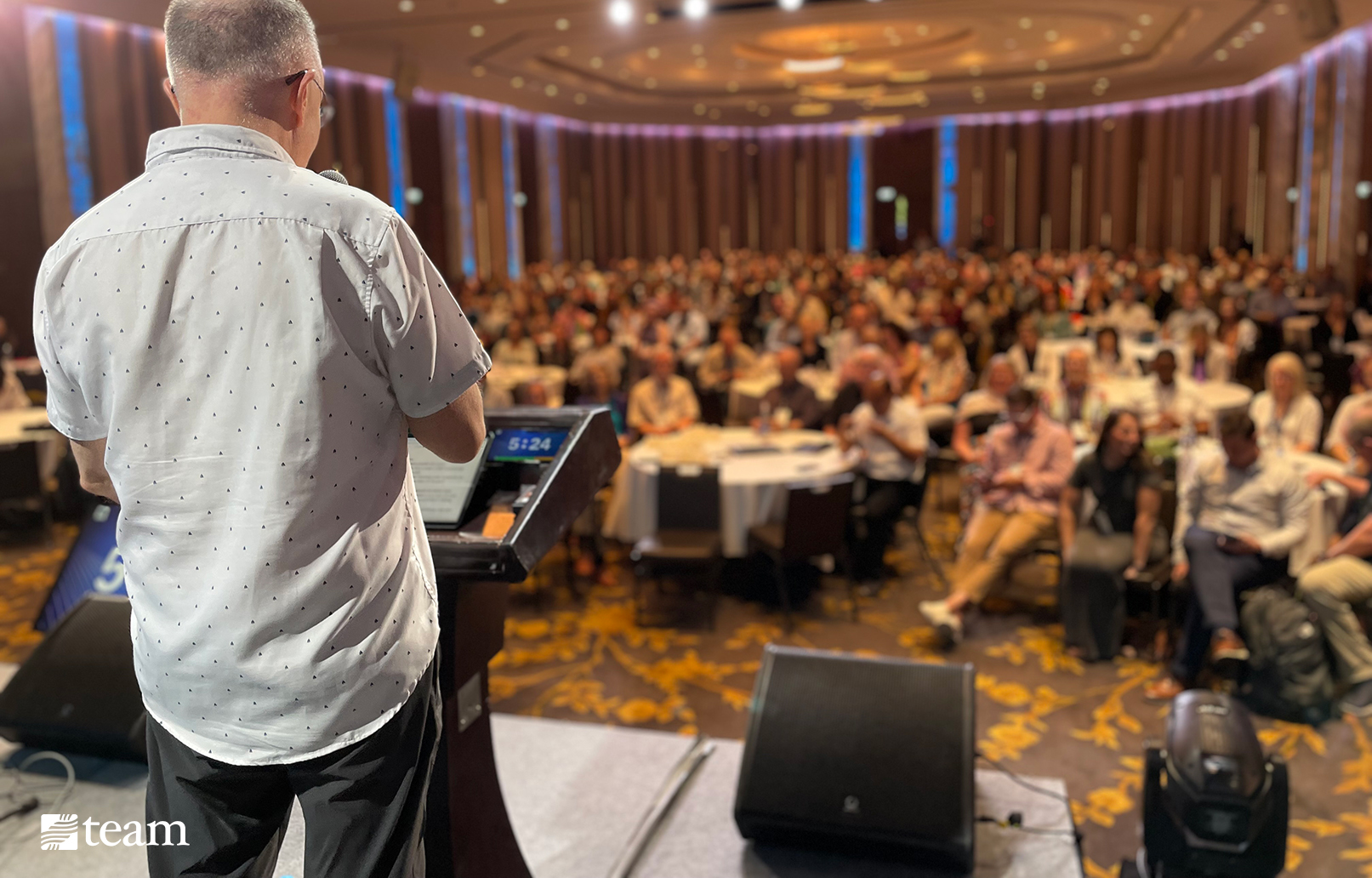 Man speaking on stage overlooking the audience.