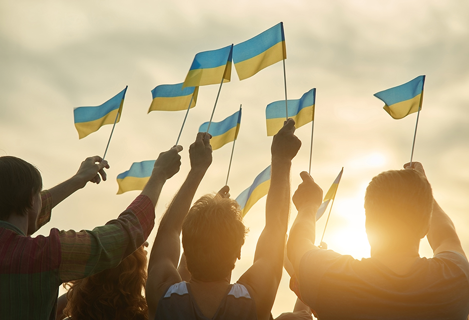 Group holding Ukraine flags at sunset.