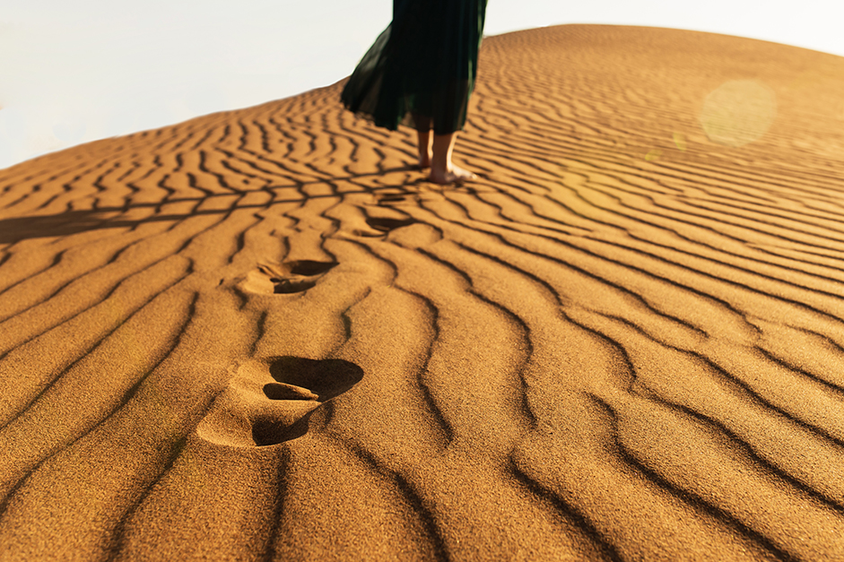 Footprints from walking in the desert sand.