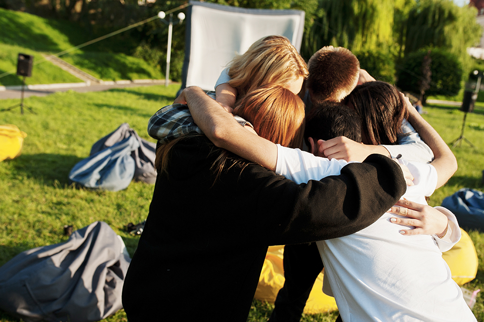 Group of friends praying in the park.