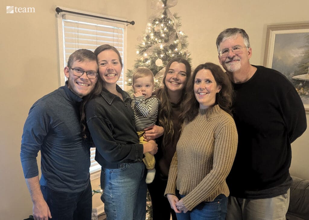 Family standing in front of a Christmas tree.